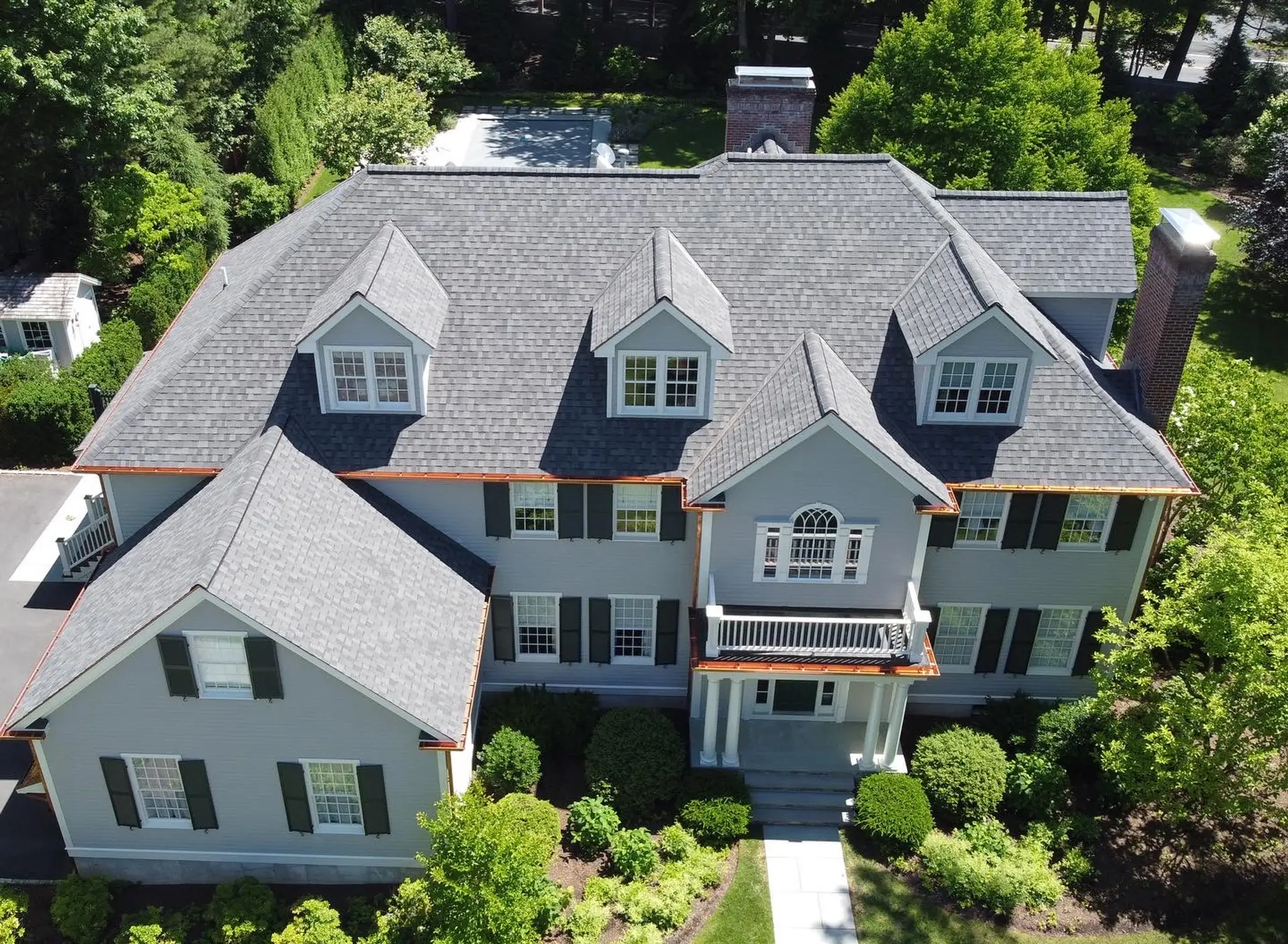 Aerial view of a completed gray architectural shingle roof with copper gutters